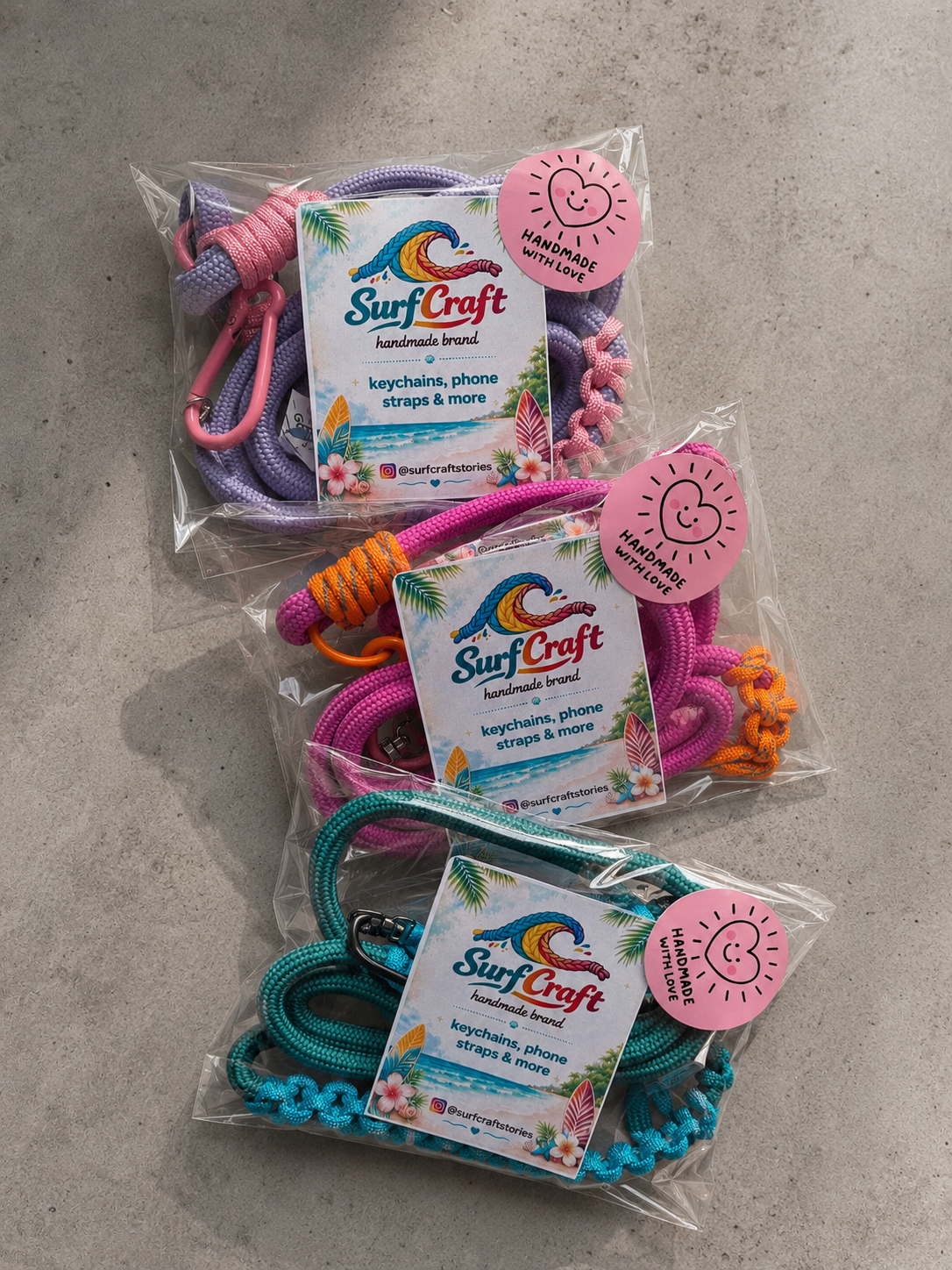 Trzy kolorowe produkty Surfcraftstories zapakowane z firmowymi kartami i naklejkami